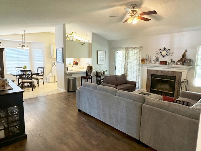 650 N Burgan Ave, Fresno, CA 93727 - living room featuring vaulted ceiling, dark wood-style flooring, ceiling fan, a tiled fireplace, and a chandelier