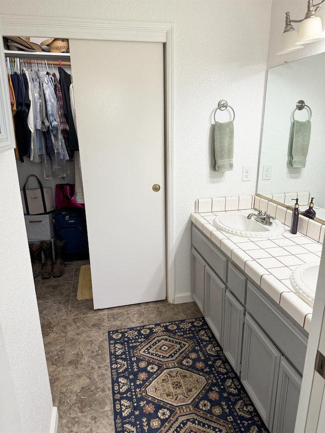 650 N Burgan Ave, Fresno, CA 93727 - bathroom with double vanity, a spacious closet, and stone finish floors