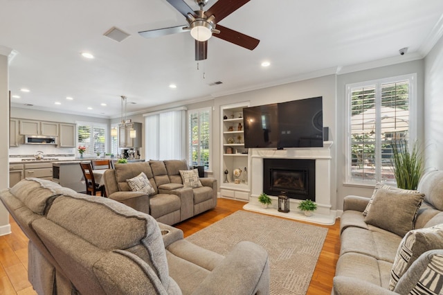 7310 N Katy Ave, Fresno, CA 93722 - living area with a ceiling fan, crown molding, light wood-style floors, a glass covered fireplace, and recessed lighting