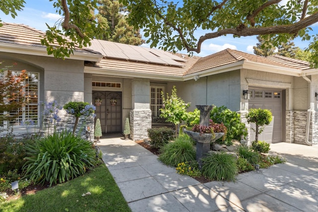 7310 N Katy Ave, Fresno, CA 93722 - view of front of home featuring stone siding, a garage, a tile roof, and roof mounted solar panels