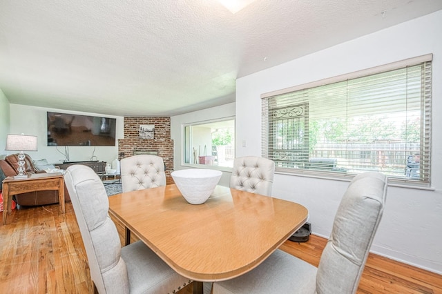 3625 E Cortland Ave, Fresno, CA 93726 - dining room featuring light wood-type flooring, a textured ceiling, and a fireplace