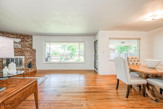 3625 E Cortland Ave, Fresno, CA 93726 - dining space with a textured ceiling, light wood-style flooring, and a brick fireplace