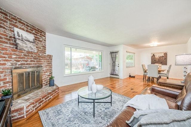 3625 E Cortland Ave, Fresno, CA 93726 - living room featuring wood finished floors, a brick fireplace, and a textured ceiling