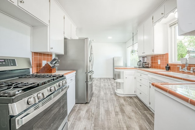 3625 E Cortland Ave, Fresno, CA 93726 - kitchen with gas range, light wood-type flooring, white cabinets, tile counters, and tasteful backsplash