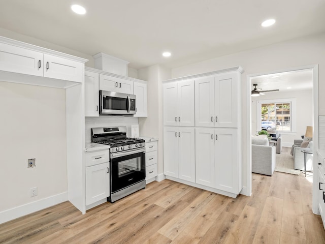 3644 E Illinois Ave, Fresno, CA 93702 - kitchen with appliances with stainless steel finishes, light wood finished floors, white cabinetry, recessed lighting, and light stone counters
