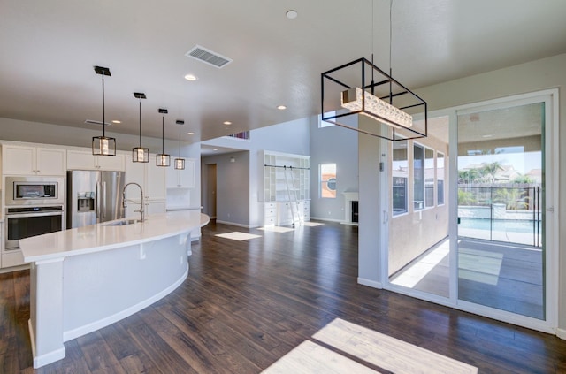 1072 Soledad Ave, Clovis, CA 93619 - kitchen featuring stainless steel appliances, light countertops, white cabinets, a kitchen island with sink, and dark wood-style flooring