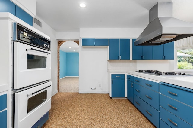 4760 N Rowell Ave, Fresno, CA 93726 - kitchen featuring island exhaust hood, blue cabinetry, white double oven, light countertops, and stainless steel gas stovetop