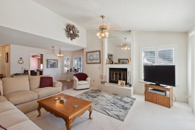 1059 E Fallbrook Ave, Fresno, CA 93720 - carpeted living room featuring a textured ceiling, a chandelier, lofted ceiling, and a tiled fireplace