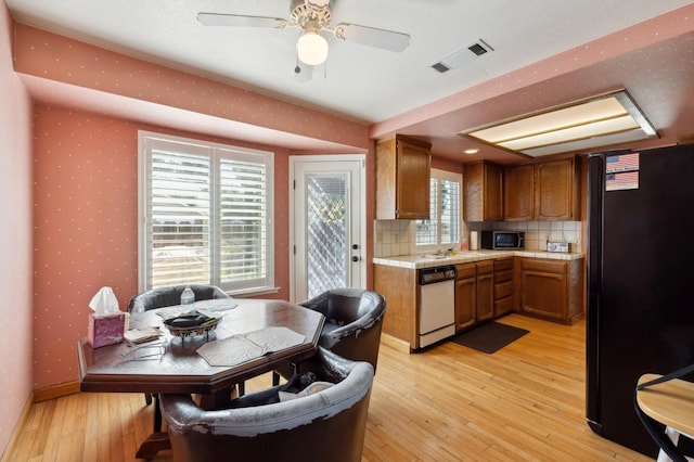 1059 E Fallbrook Ave, Fresno, CA 93720 - kitchen with freestanding refrigerator, white dishwasher, brown cabinets, light wood finished floors, and decorative backsplash