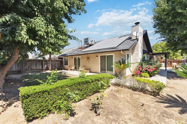 1059 E Fallbrook Ave, Fresno, CA 93720 - rear view of house featuring stucco siding, a fenced backyard, roof mounted solar panels, a chimney, and a patio area