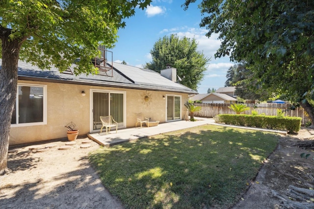 1059 E Fallbrook Ave, Fresno, CA 93720 - rear view of property with stucco siding, roof mounted solar panels, a patio area, and a chimney