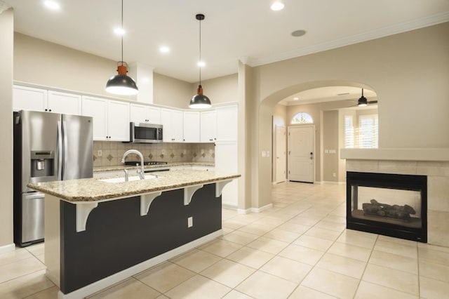3613 Utah Ln, Clovis, CA 93619 - kitchen with appliances with stainless steel finishes, tasteful backsplash, arched walkways, a breakfast bar area, and crown molding