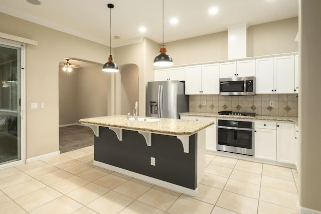 3613 Utah Ln, Clovis, CA 93619 - kitchen featuring stainless steel appliances, light tile patterned floors, a breakfast bar area, decorative backsplash, and a kitchen island with sink