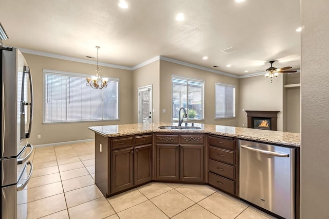 2663 E Spice Way, Fresno, CA 93720 - kitchen with appliances with stainless steel finishes, a ceiling fan, light tile patterned floors, a glass covered fireplace, and dark brown cabinets