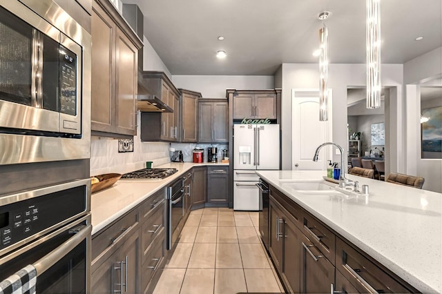 2076 Chennault Ave, Clovis, CA 93611 - kitchen featuring stainless steel appliances, light countertops, light tile patterned floors, dark brown cabinetry, and decorative backsplash