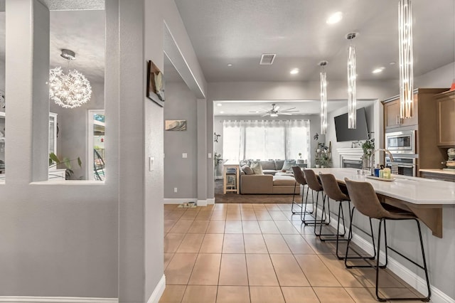 2076 Chennault Ave, Clovis, CA 93611 - kitchen featuring stainless steel appliances, a kitchen bar, light countertops, a ceiling fan, and light tile patterned floors
