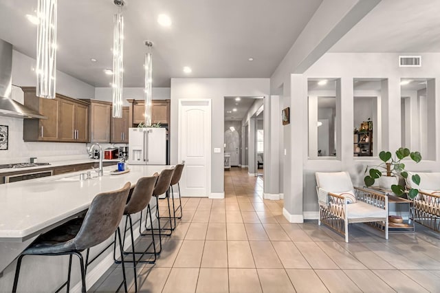2076 Chennault Ave, Clovis, CA 93611 - kitchen featuring freestanding refrigerator, premium range hood, light tile patterned flooring, a kitchen bar, and stainless steel gas stovetop