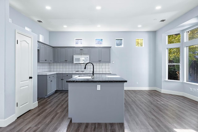 5667 W Bluff Ave, Fresno, CA 93722 - kitchen with gray cabinets, white microwave, a center island with sink, dark wood-type flooring, and recessed lighting