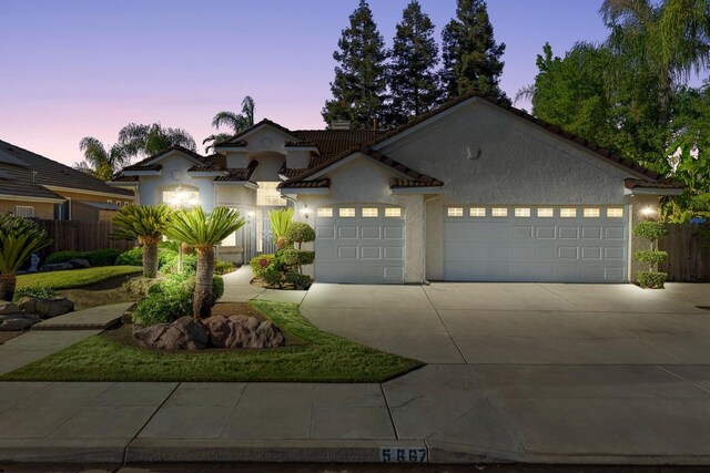 5667 W Bluff Ave, Fresno, CA 93722 - view of front of home with concrete driveway, an attached garage, stucco siding, and a tiled roof
