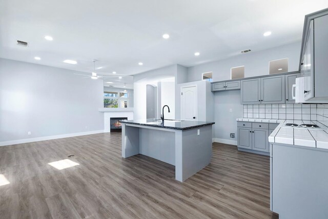 5667 W Bluff Ave, Fresno, CA 93722 - kitchen featuring ceiling fan, wood finished floors, a kitchen island with sink, tasteful backsplash, and recessed lighting