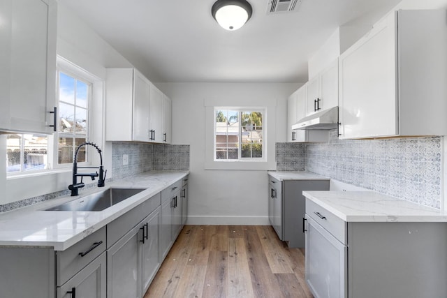 2401 E Hedges Ave, Fresno, CA 93703 - kitchen with under cabinet range hood, light wood-style flooring, gray cabinets, and light stone countertops