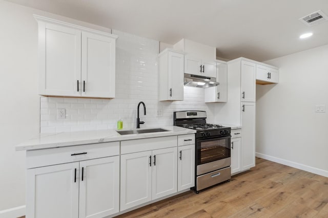 1931 W Ashlan Ave, Fresno, CA 93705 - kitchen featuring gas range, under cabinet range hood, backsplash, white cabinetry, and light wood finished floors