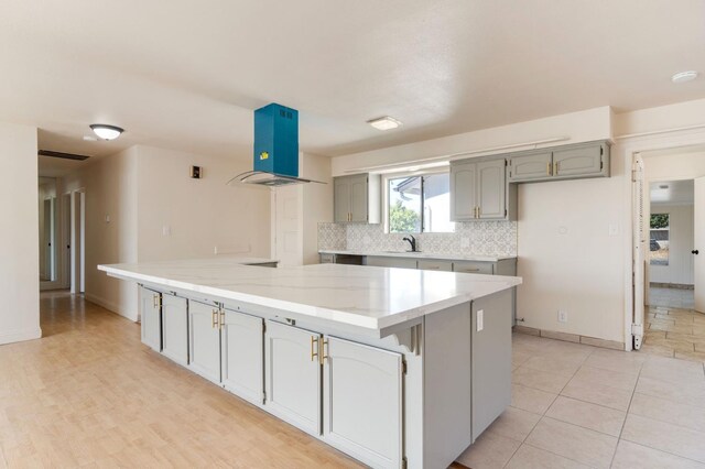 2738 S Fairway Ct, Visalia, CA 93277 - kitchen featuring ventilation hood, gray cabinets, tasteful backsplash, light stone counters, and a large island