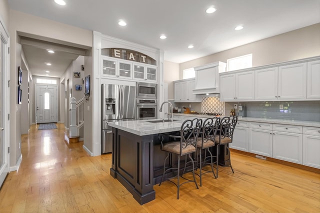 2143 Everglade Ave, Clovis, CA 93619 - kitchen featuring stainless steel appliances, a kitchen breakfast bar, decorative backsplash, light wood-style flooring, and recessed lighting
