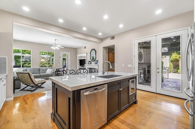 2143 Everglade Ave, Clovis, CA 93619 - kitchen with appliances with stainless steel finishes, light countertops, light wood-style floors, a center island with sink, and french doors