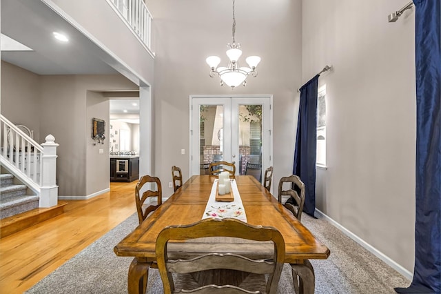 2143 Everglade Ave, Clovis, CA 93619 - dining room featuring stairs, a chandelier, french doors, a towering ceiling, and light wood-style floors