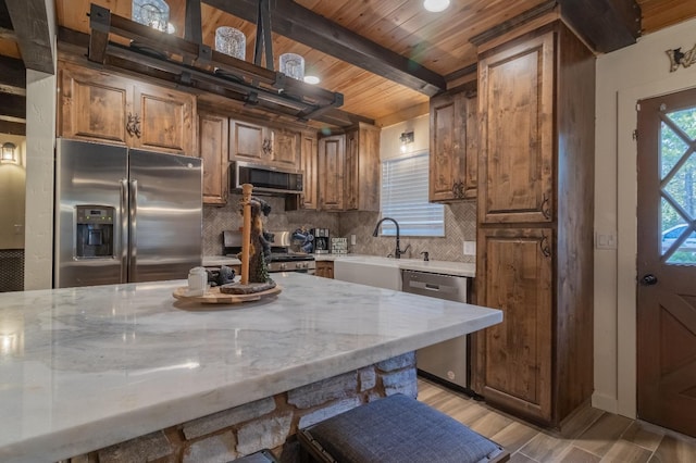 36118 Teaford Poyah, North Fork, CA 93643 - kitchen featuring appliances with stainless steel finishes, decorative backsplash, a wooden ceiling with exposed beams, light stone counters, and brown cabinetry