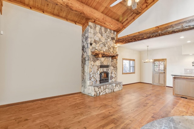 39801 Woody Ln, Shaver Lake, CA 93664 - unfurnished living room with a chandelier, a ceiling fan, light wood-type flooring, a stone fireplace, and a wood ceiling with exposed beams
