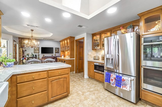 1721 W Wrenwood Ave, Fresno, CA 93711 - kitchen with appliances with stainless steel finishes, a raised ceiling, a chandelier, light countertops, and glass insert cabinets