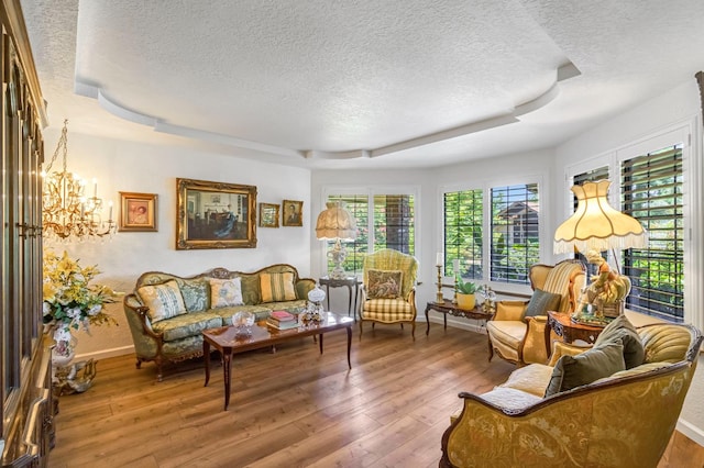 1721 W Wrenwood Ave, Fresno, CA 93711 - living room featuring a textured ceiling, a tray ceiling, hardwood / wood-style flooring, and a chandelier