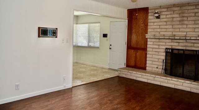 6061 N 9th St, Fresno, CA 93710 - unfurnished living room with wood finished floors, a brick fireplace, and a textured ceiling