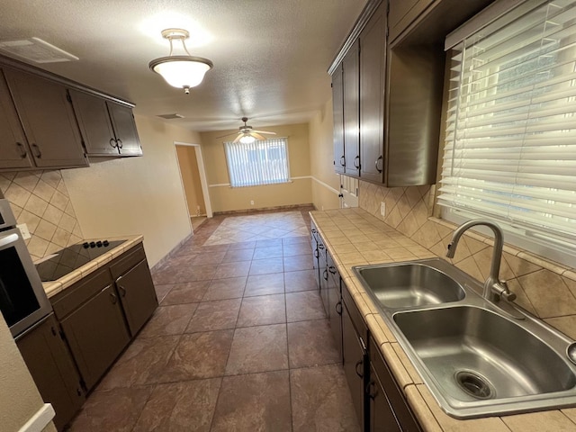 4308 N Cedar Ave, Fresno, CA 93726 - kitchen featuring tile countertops, black electric stovetop, backsplash, a ceiling fan, and a textured ceiling