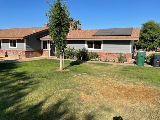 6589 N De Wolf Ave N, Clovis, CA 93619 - back of property with roof mounted solar panels, brick siding, and a lawn