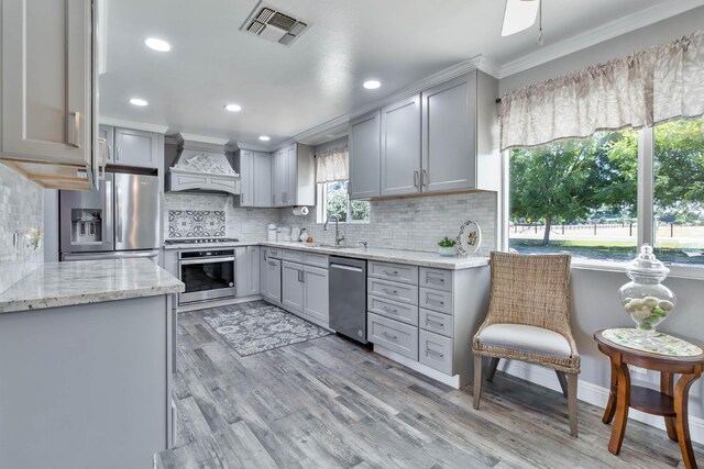 6589 N De Wolf Ave N, Clovis, CA 93619 - kitchen with stainless steel appliances, custom exhaust hood, gray cabinets, decorative backsplash, and light stone counters