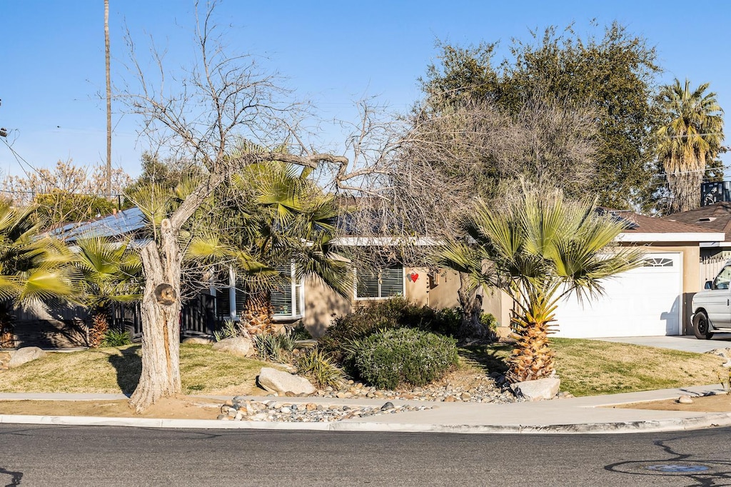 4404 N Eddy Ave, Fresno, CA 93727 - obstructed view of property featuring an attached garage, driveway, and stucco siding