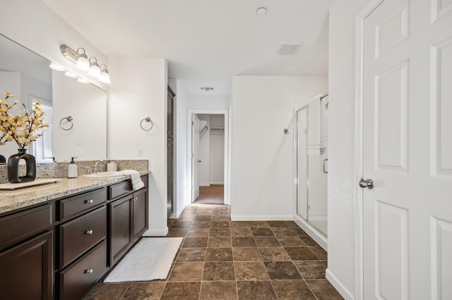 7141 N Shiraz Ave, Fresno, CA 93722 - bathroom featuring vanity, a shower stall, a spacious closet, and stone finish flooring