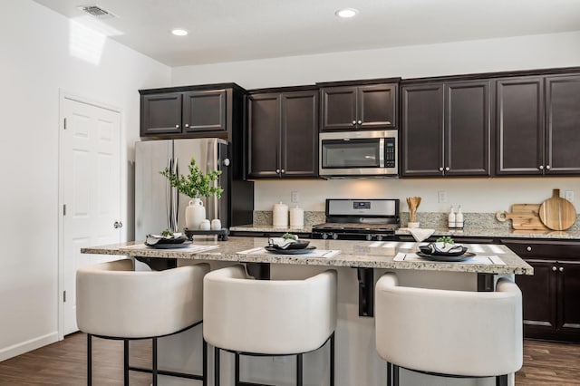 7141 N Shiraz Ave, Fresno, CA 93722 - kitchen featuring appliances with stainless steel finishes, a breakfast bar area, dark wood-style floors, and recessed lighting