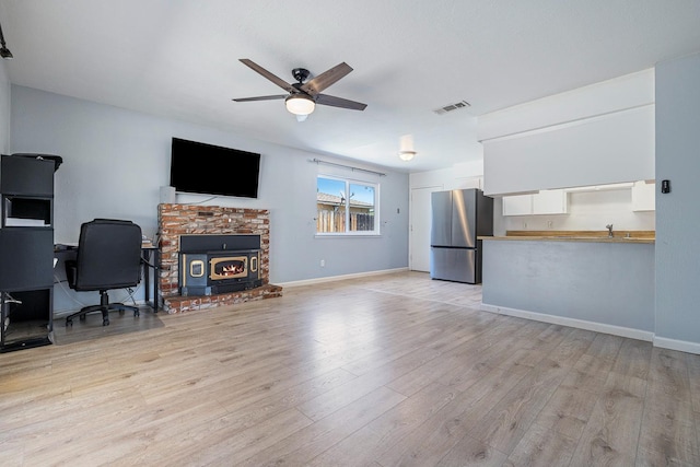 3318 Stanford Ave, Clovis, CA 93611 - living room featuring a ceiling fan, light wood finished floors, and a wood stove