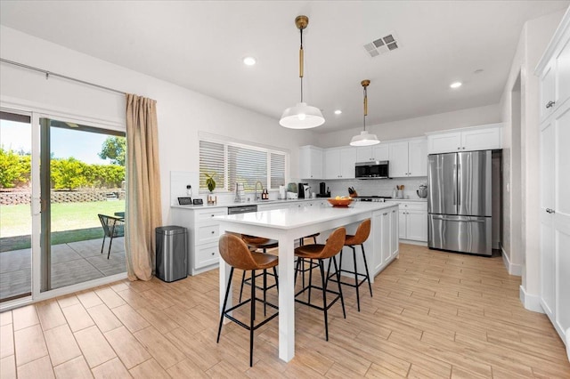 859 Windmill Ave, Clovis, CA 93619 - kitchen featuring appliances with stainless steel finishes, light countertops, white cabinetry, a breakfast bar area, and a kitchen island