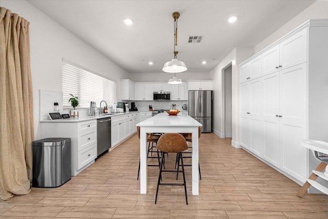 859 Windmill Ave, Clovis, CA 93619 - kitchen featuring stainless steel appliances, light countertops, white cabinets, a breakfast bar, and recessed lighting