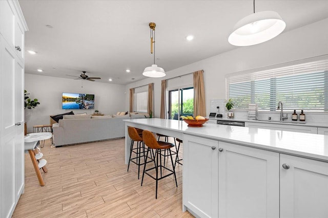 859 Windmill Ave, Clovis, CA 93619 - kitchen with light wood-style floors, light countertops, white cabinetry, open floor plan, and hanging light fixtures