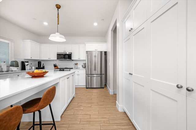 859 Windmill Ave, Clovis, CA 93619 - kitchen with stainless steel appliances, tasteful backsplash, light countertops, white cabinets, and light wood-style flooring