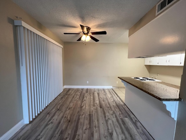 1205 F St, Reedley, CA 93654 - kitchen featuring a ceiling fan, wood finished floors, a textured ceiling, white cabinets, and white cooktop