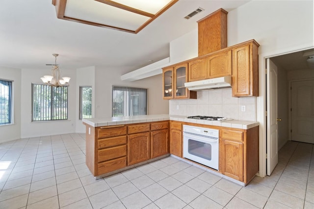 122 E Loop, Madera, CA 93637 - kitchen with white appliances, under cabinet range hood, tile counters, and light tile patterned flooring