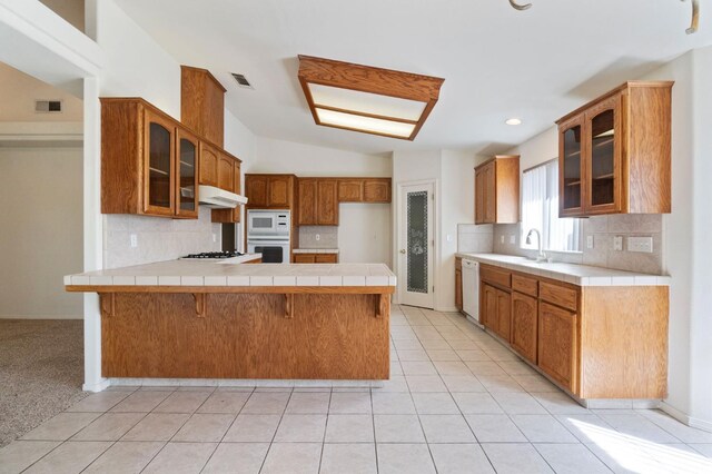 122 E Loop, Madera, CA 93637 - kitchen with white appliances, a peninsula, under cabinet range hood, glass insert cabinets, and tasteful backsplash