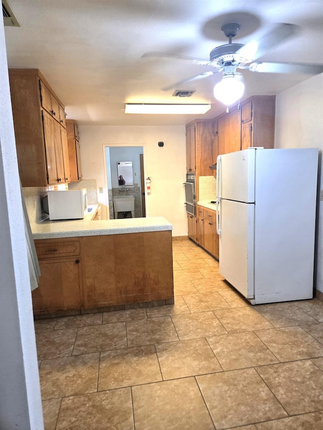 5525 S Fig Ave, Fresno, CA 93706 - kitchen featuring white appliances, ceiling fan, brown cabinetry, and light countertops